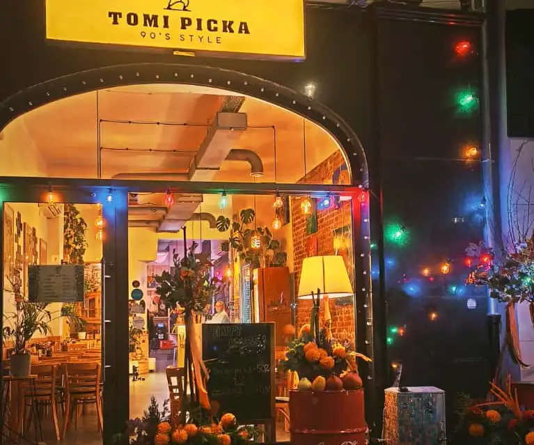 Witryna Tomi Picka nocą z żółtym szyldem i lampkami