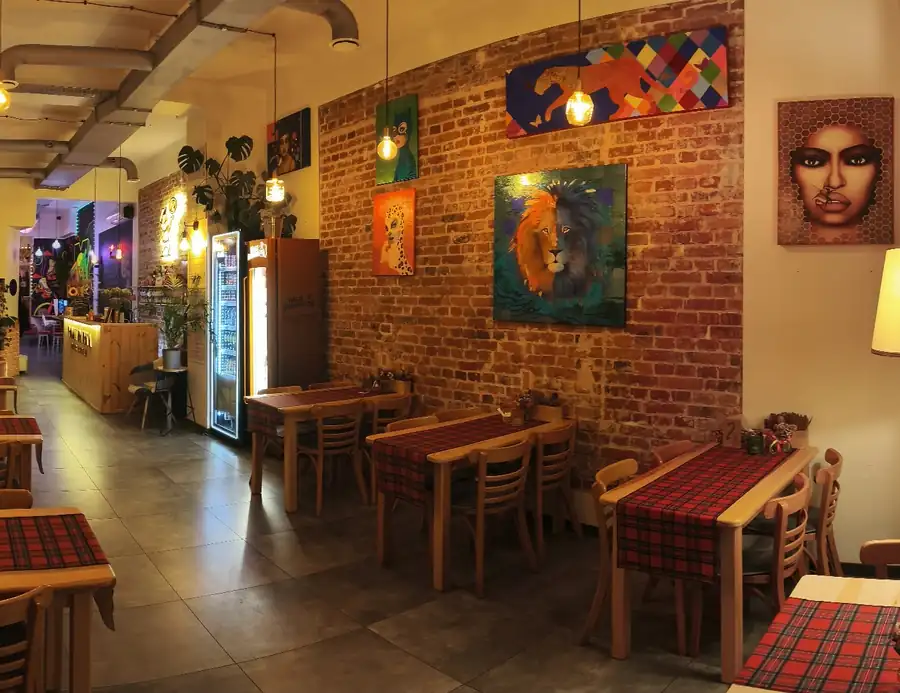 Sala Tomi Picka z drewnianymi stołami, ceglaną ścianą i lampami